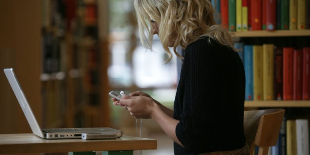 En ung kvinna tittar på sin MP3-spelare på ett bibliotek, (Foto: Fredrik Sandberg/TT)
