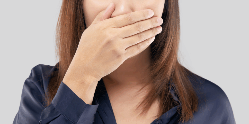 Person som täcker munnen med handen för att illustrera en farlig mening man inte bör säga på en intervju.