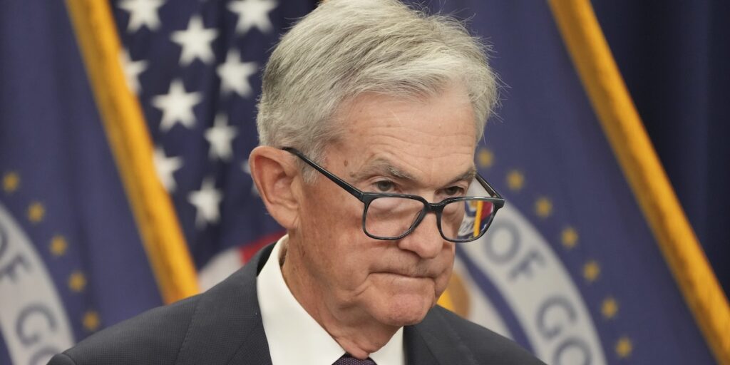 Jerome Powell vid podiet under Fed-presskonferens, med amerikansk flagga i bakgrunden.